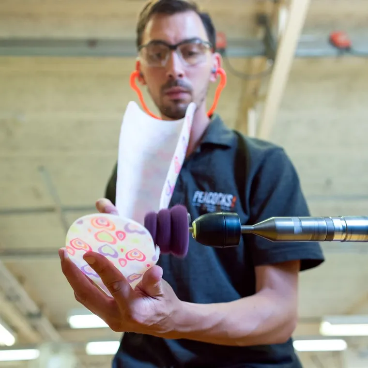 A technician shaping a custom-made foot orthotic in a workshop