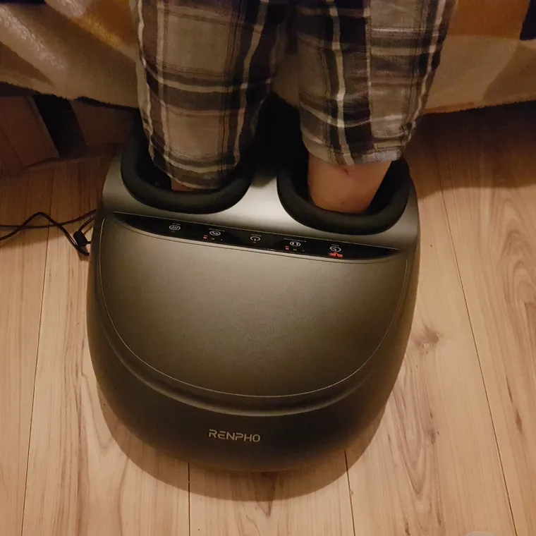 An electric foot massager device with a moulded footbed on a plain background