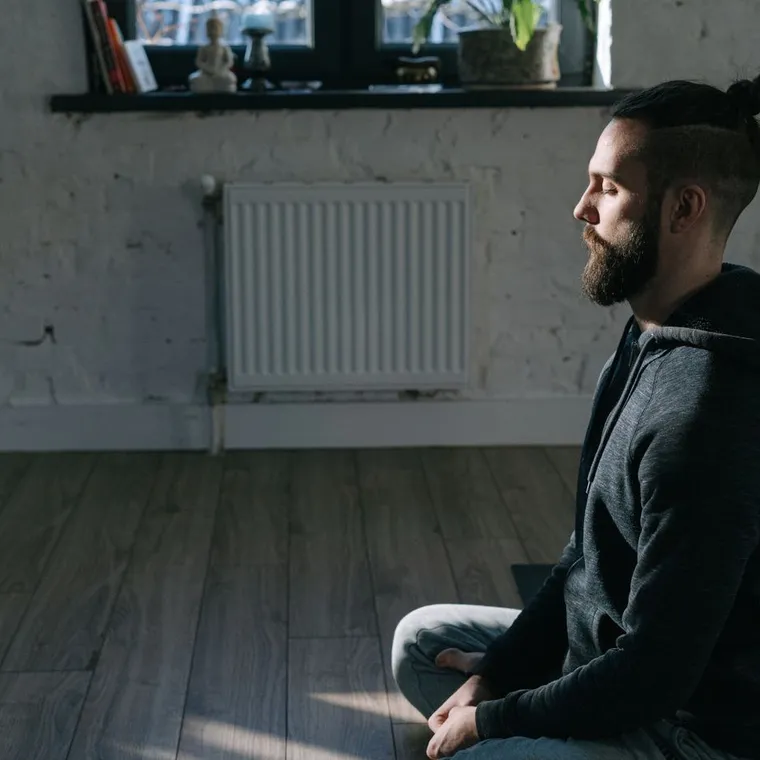 Person sitting quietly at home with eyes closed doing a short breathing practice